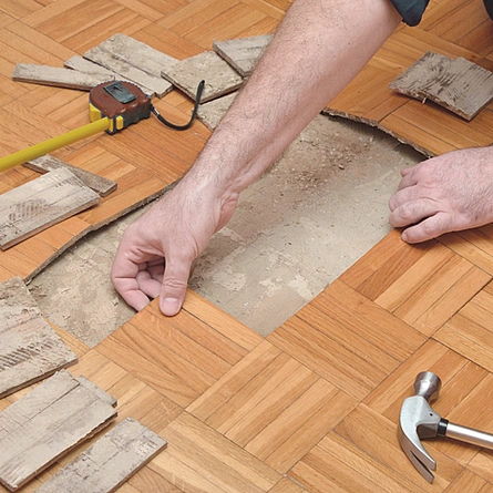 Reparatur Parkett, Laminat, Designbelag - Handwerker entfernt beschädigtes Parkett, Erneuerung von Holzfußboden